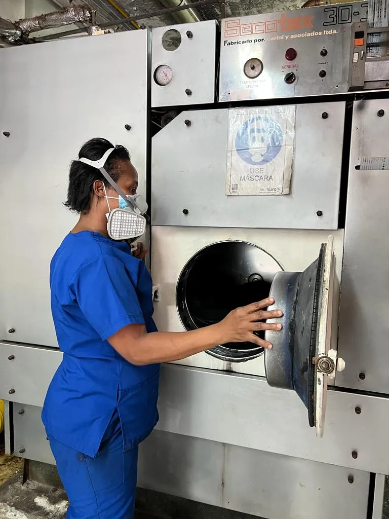 Operaria con mascarilla en la máquina de lavado en seco